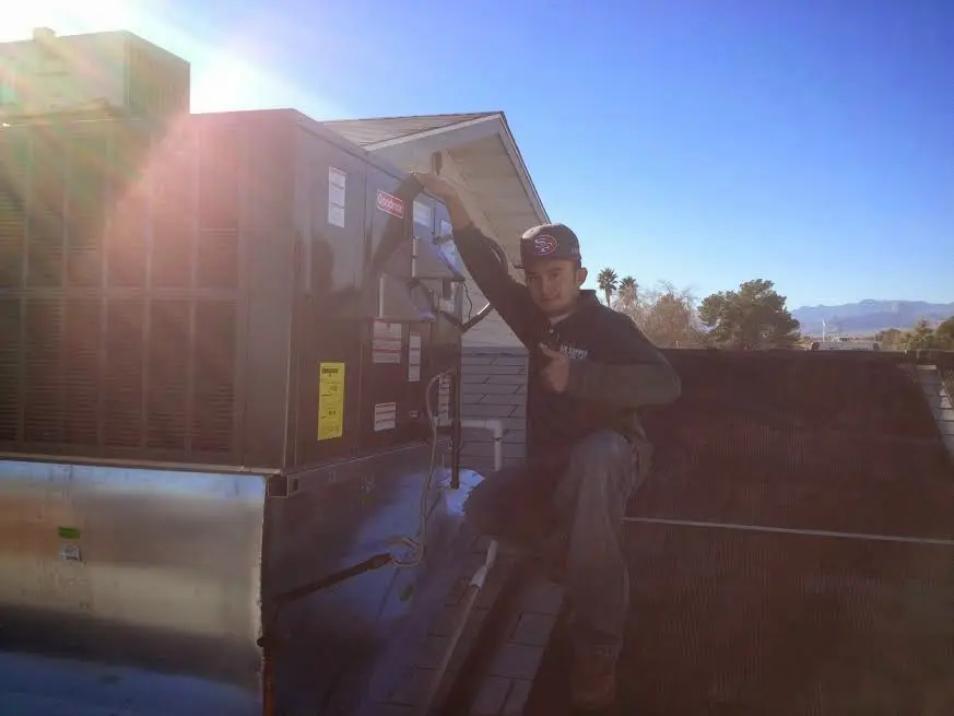 HVAC technician performing Air Duct Cleaning on a rooftop unit in Baxter